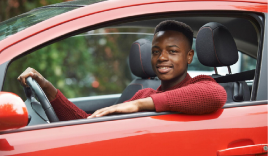 Young man smiling in the driver's seat of a car.